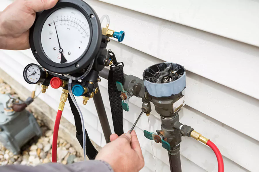 Licensed technician performing a certified backflow test and inspection on a residential device in Highland Park