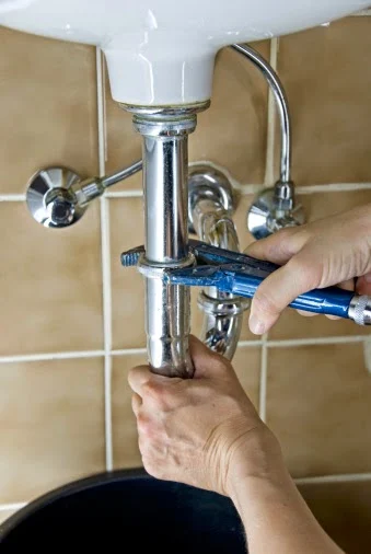 A professional plumber tightening a sink drain pipe to prevent leaks, ensuring reliable service in Glencoe